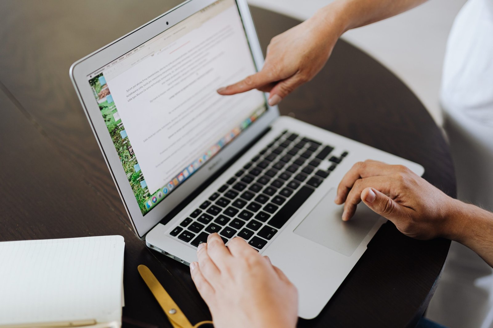 Two people collaborating on a project using a laptop in an office setting.