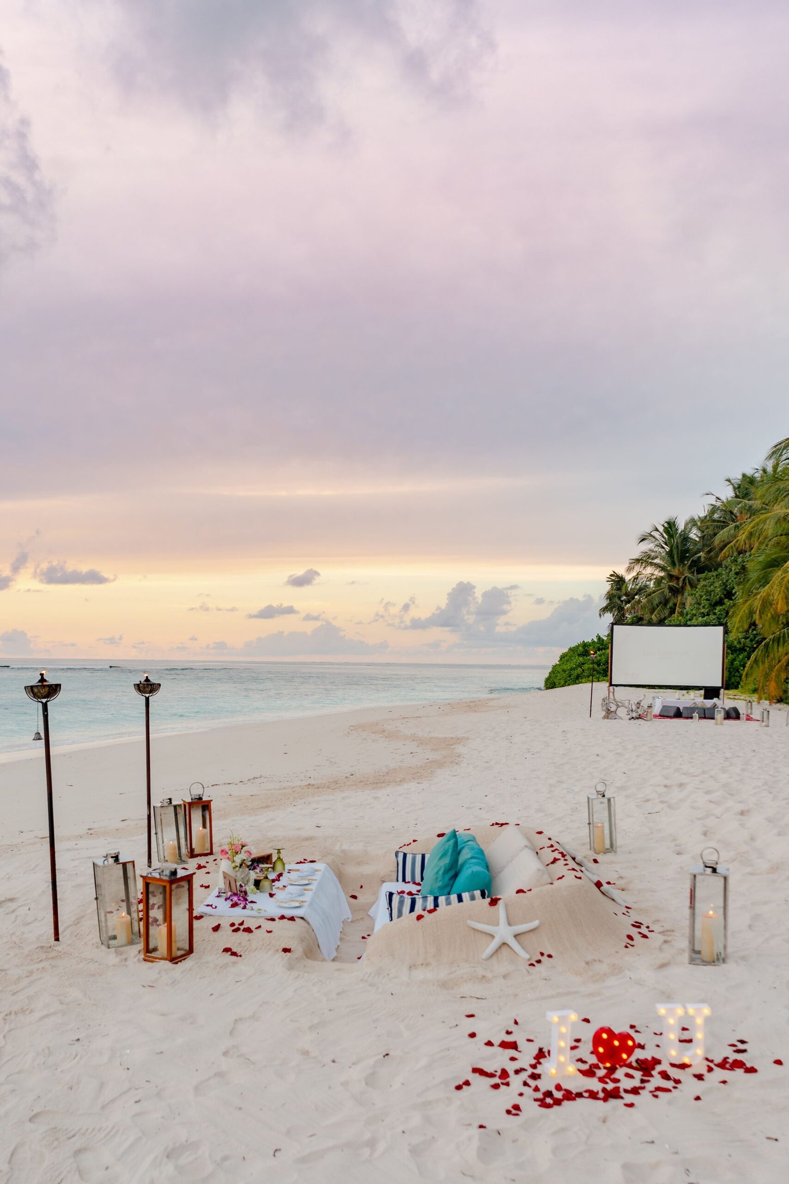 Beautiful and intimate beach setup with romantic decorations at sunset on a sandy shore.